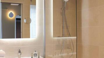 Une salle de bain moderne avec une douche à parois de verre, un meuble-lavabo avec un miroir et un porte-serviettes.