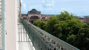 Un balcón con vista a un edificio histórico con cúpula verde y ventanas de arco.