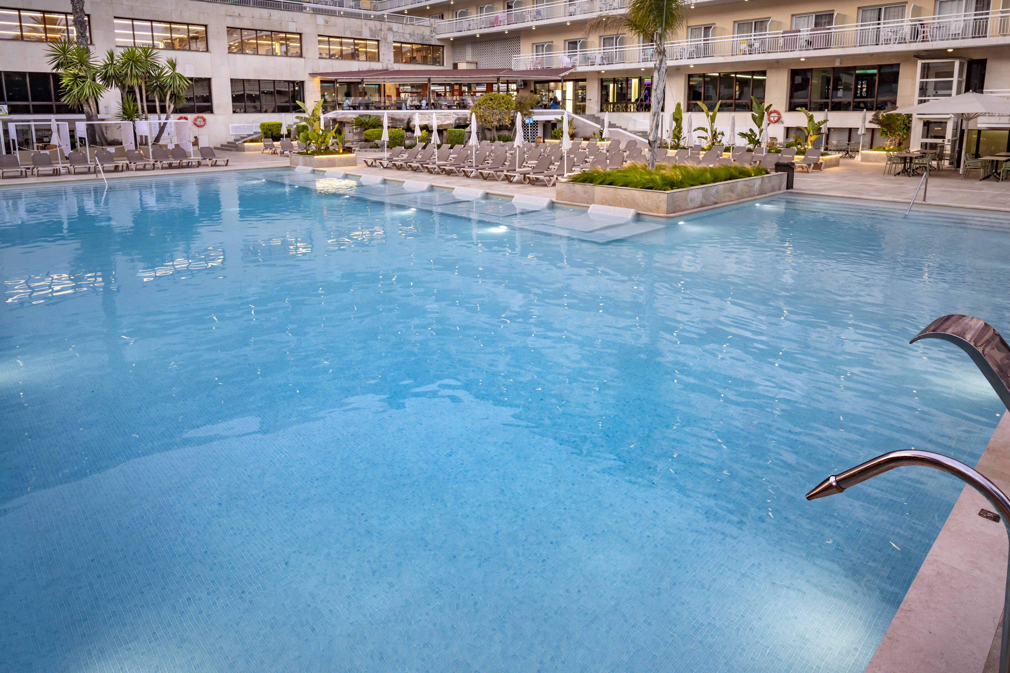 A large indoor swimming pool with multiple levels of balconies and lounge areas.