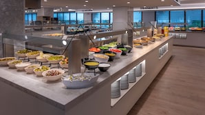 Un espace buffet proposant différents stands de restauration, notamment des salades, des fruits et des desserts.