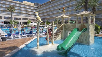 Relax by the pool surrounded by lounge chairs and umbrellas, with a children's play area nearby.