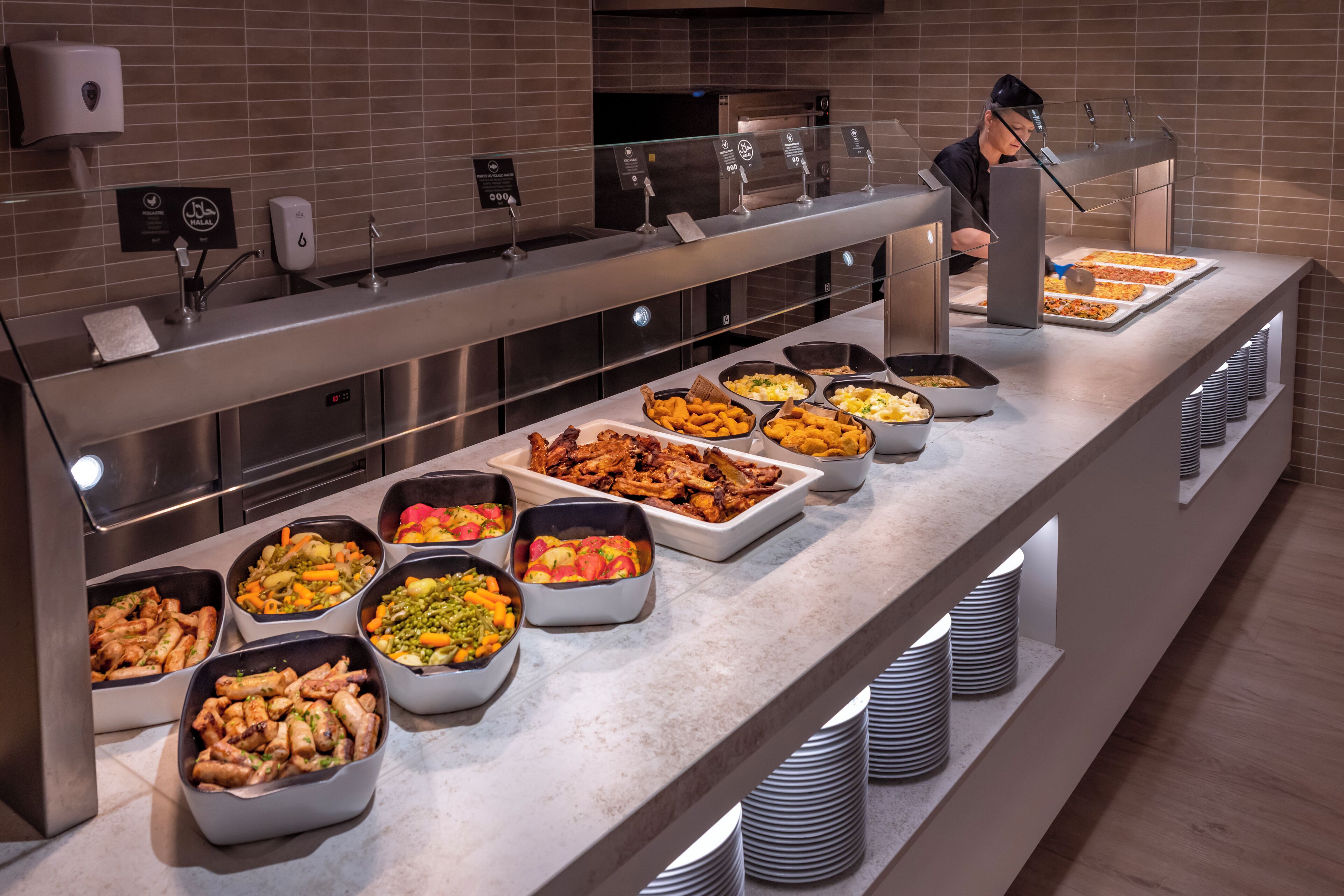 Un buffet proposant une variété de plats et une personne qui sert les clients.