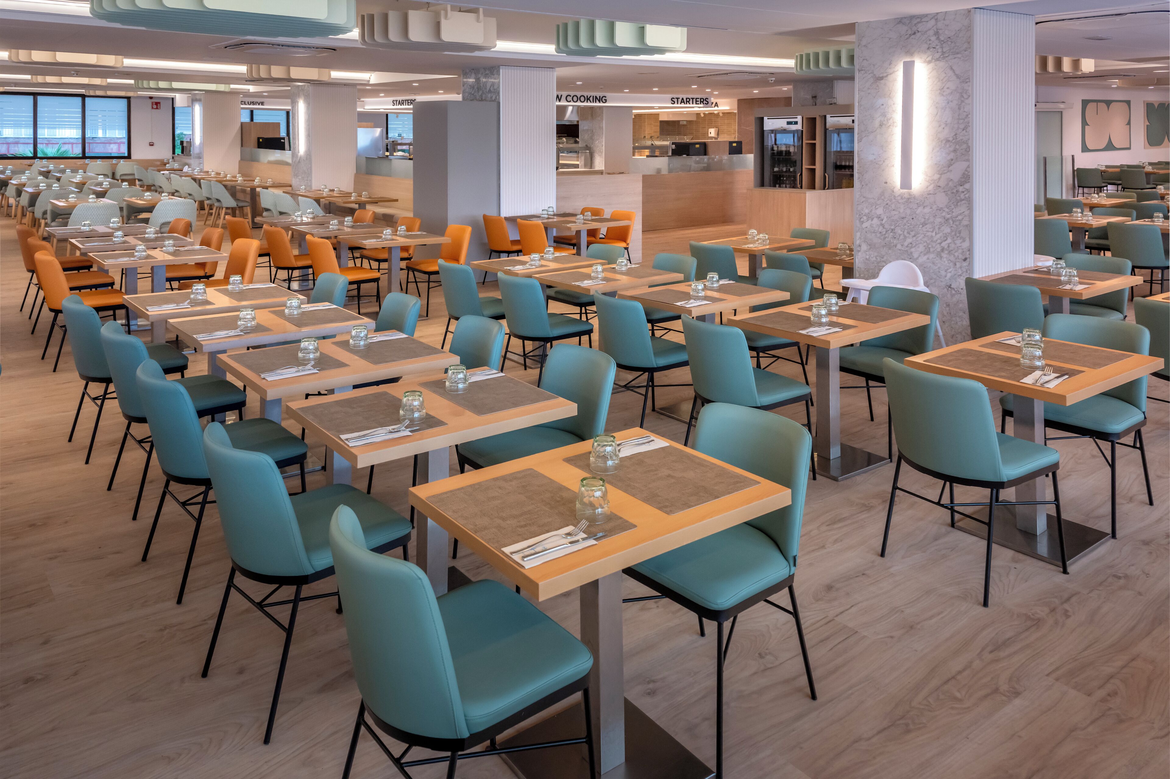 Un comedor amplio con varias mesas y sillas, una zona de cocina y un espacio de estar con vistas.
