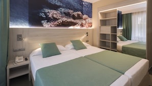 Une chambre d’hôtel avec deux lits, une literie verte, une tête de lit en bois, une table de chevet avec un téléphone et un grand tableau au-dessus des lits.
