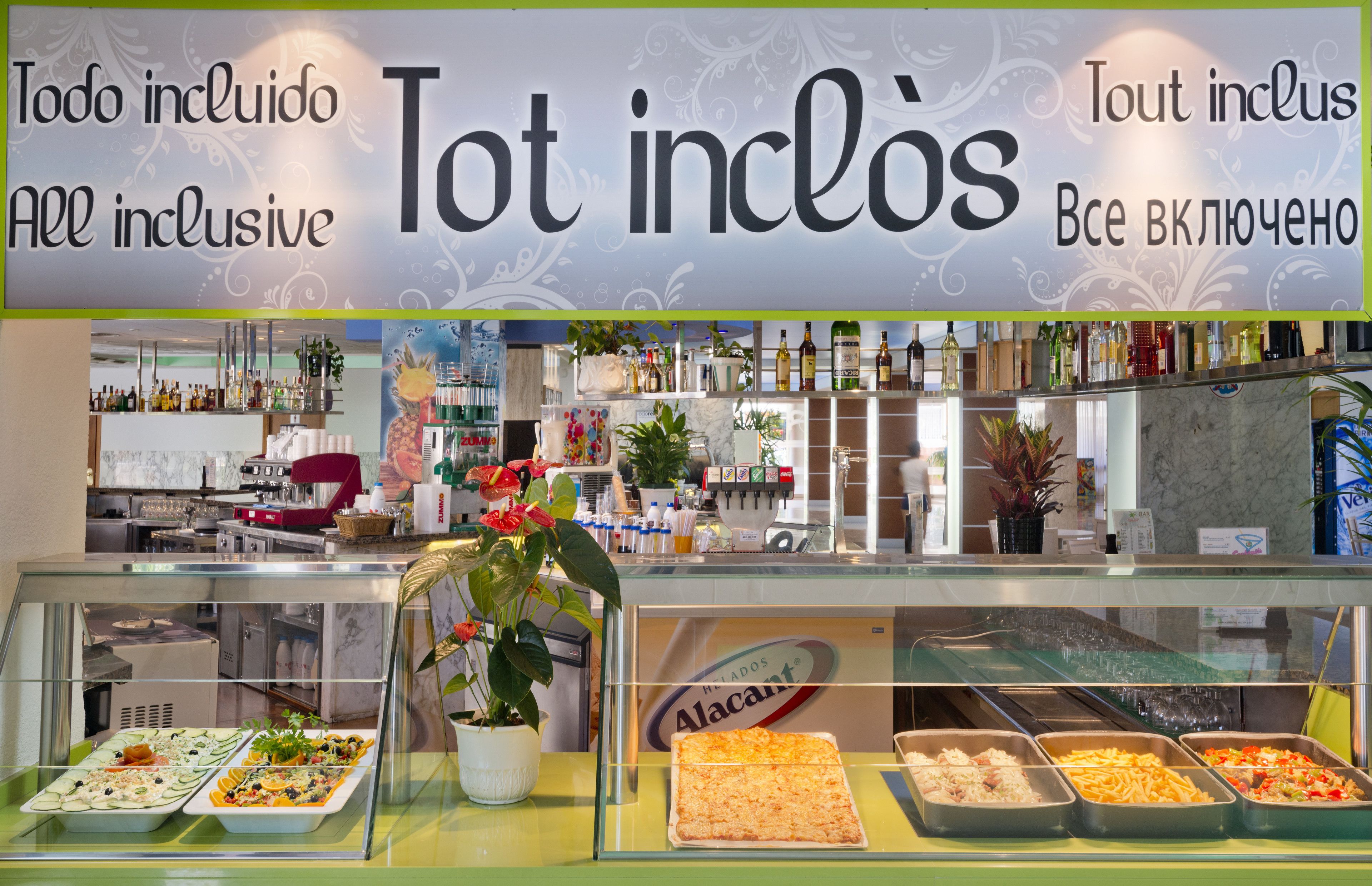 Un área de bufé con diversas opciones de comida y un letrero que indica 'Tot Inclus' o 'Todo incluido'.