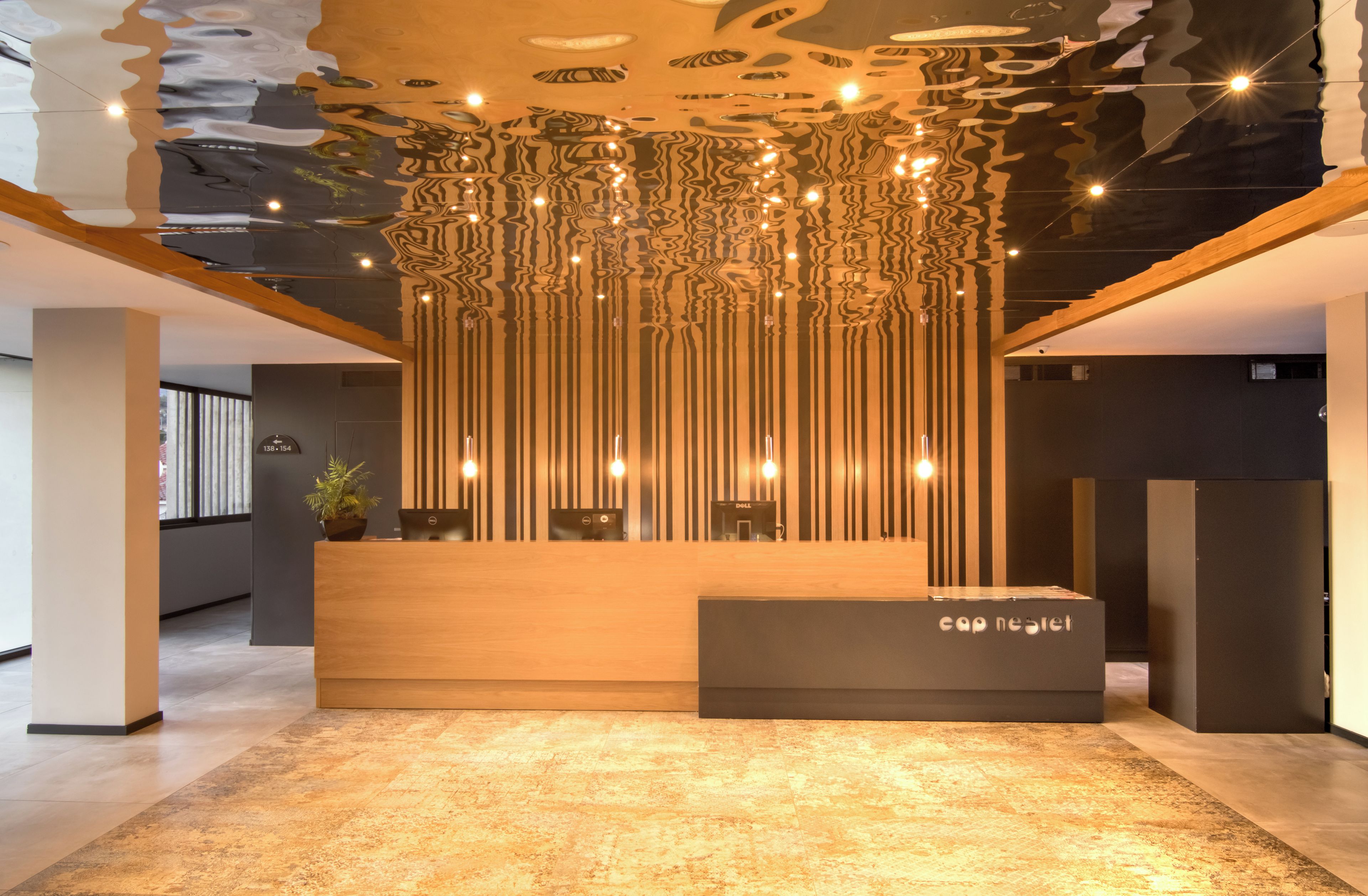 A reception desk with a modern design, a wooden reception area, and a ceiling with a unique light fixture.