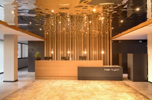 Un comptoir d’accueil au design moderne, un espace d’accueil en bois et un plafond agrémenté d’un luminaire original.