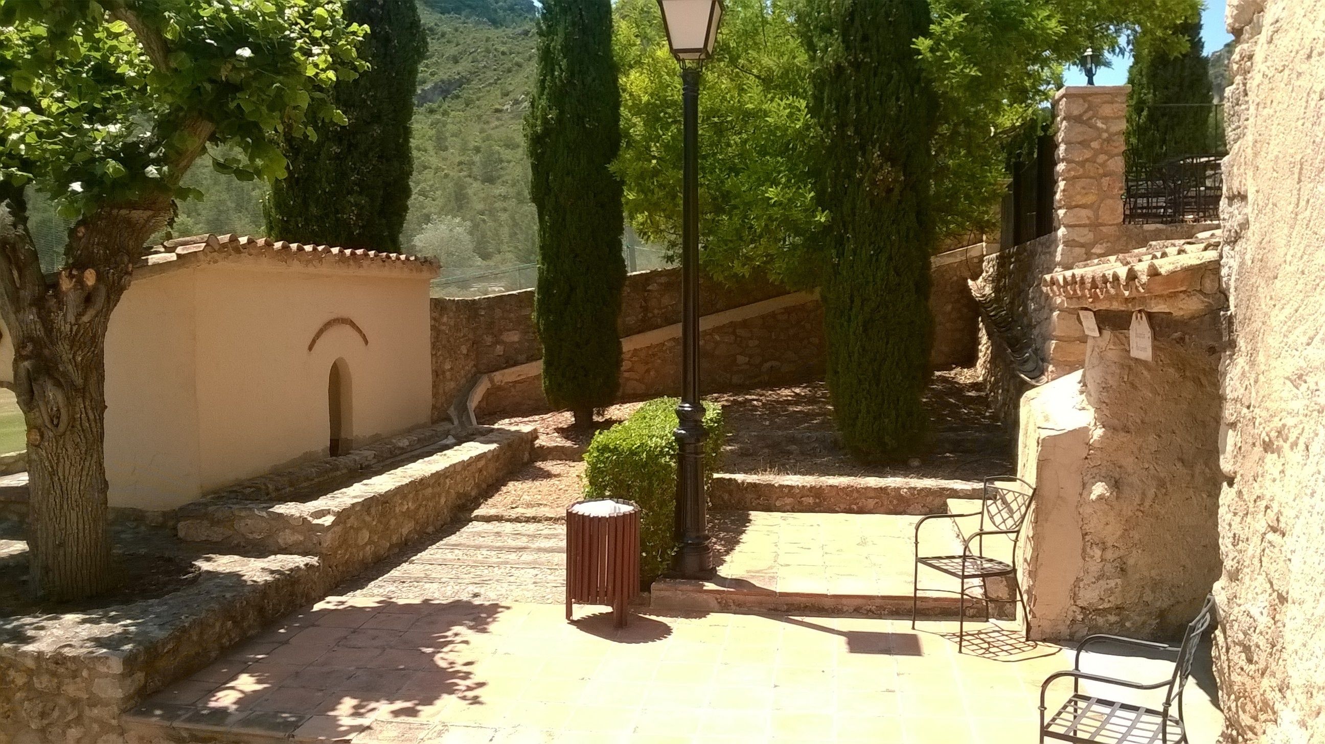 A courtyard with stone walls, a lamp post, and a bench.