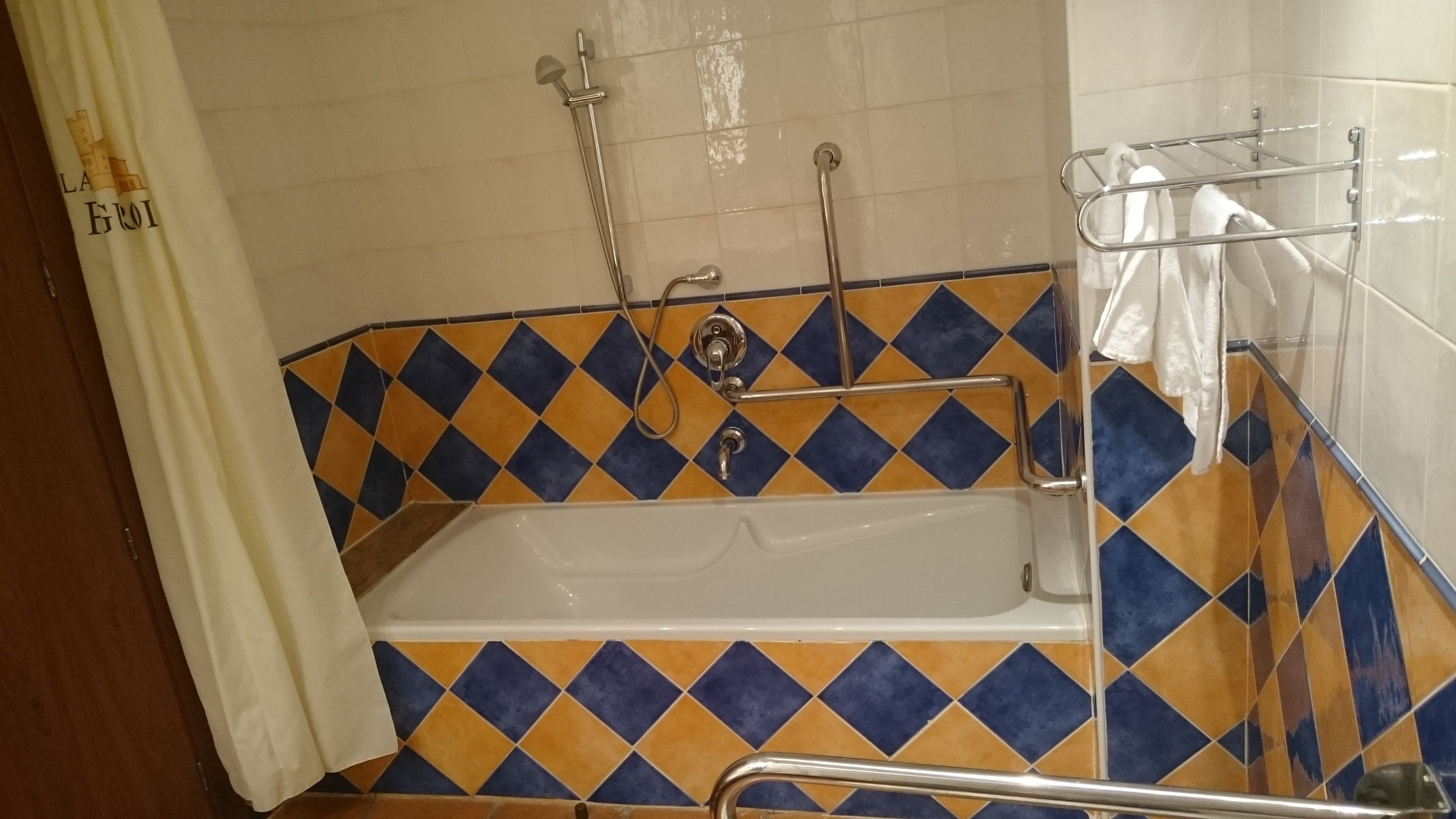 A bathroom with a bathtub, a shower, and a handrail.