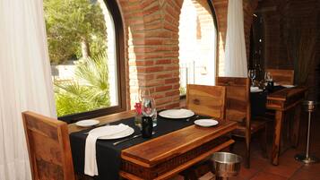 Comedor con pared de ladrillo, muebles de madera y vista a la vegetación.