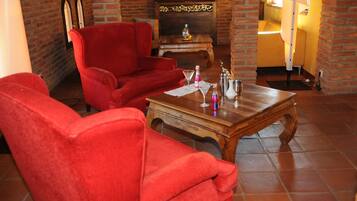 Una sala de estar acogedora con sofás de terciopelo rojo, una mesa de centro de madera y una chimenea de ladrillo.