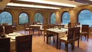 A restaurant with brick arches and large windows, wooden tables and chairs, and a tiled floor. - La Figuerola Hotel & Restaurant (Vandellos i l'Hospitalet de l'Infant)