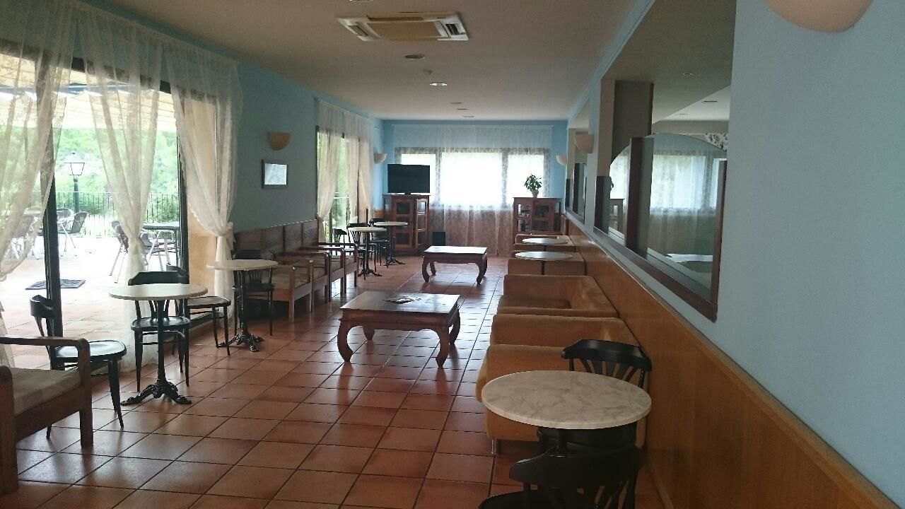 A spacious indoor area with multiple seating arrangements, including tables and chairs, and a television mounted on the wall.