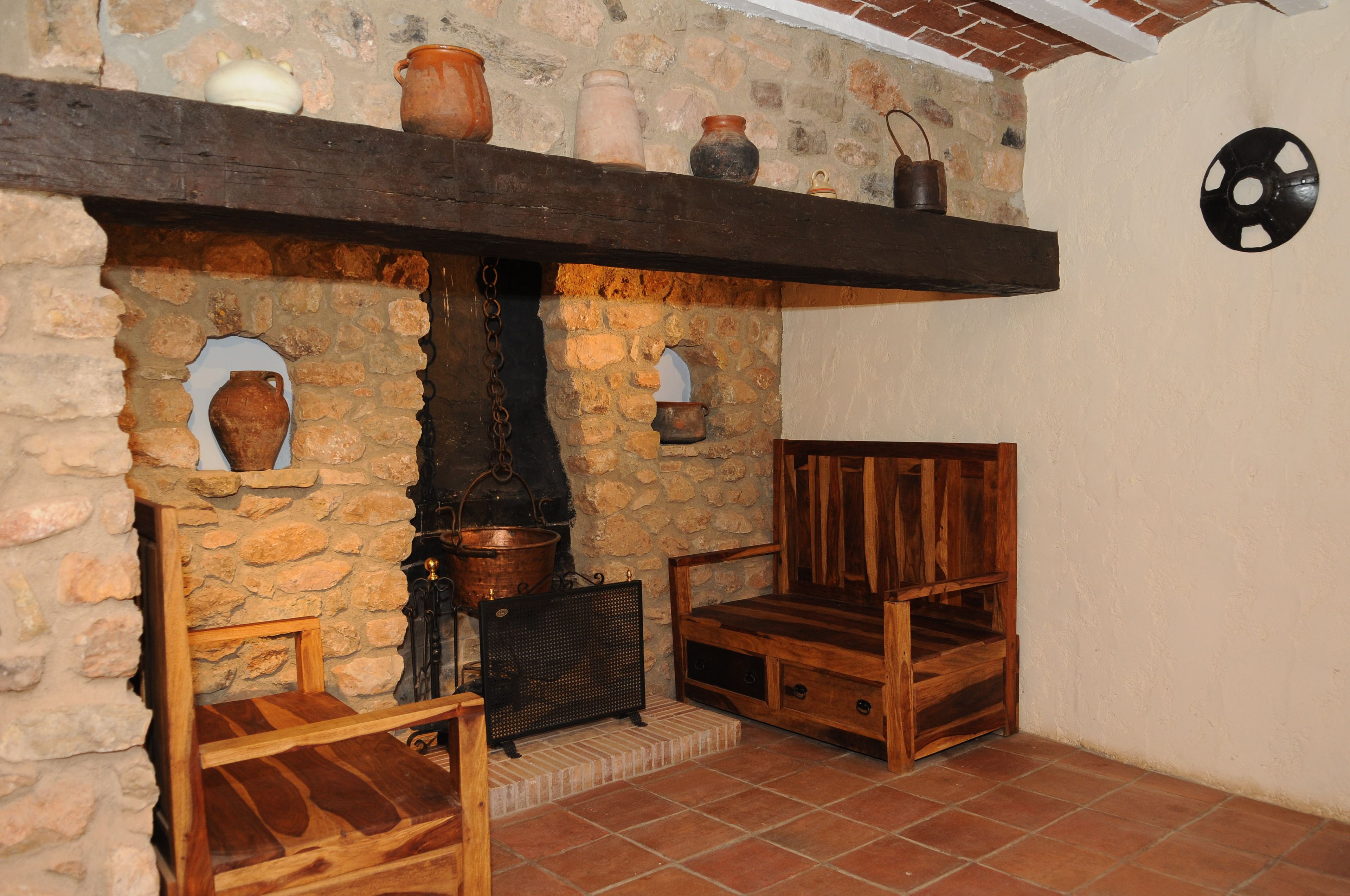 Une cheminée en pierre rustique, avec un banc en bois et une étagère au-dessus.