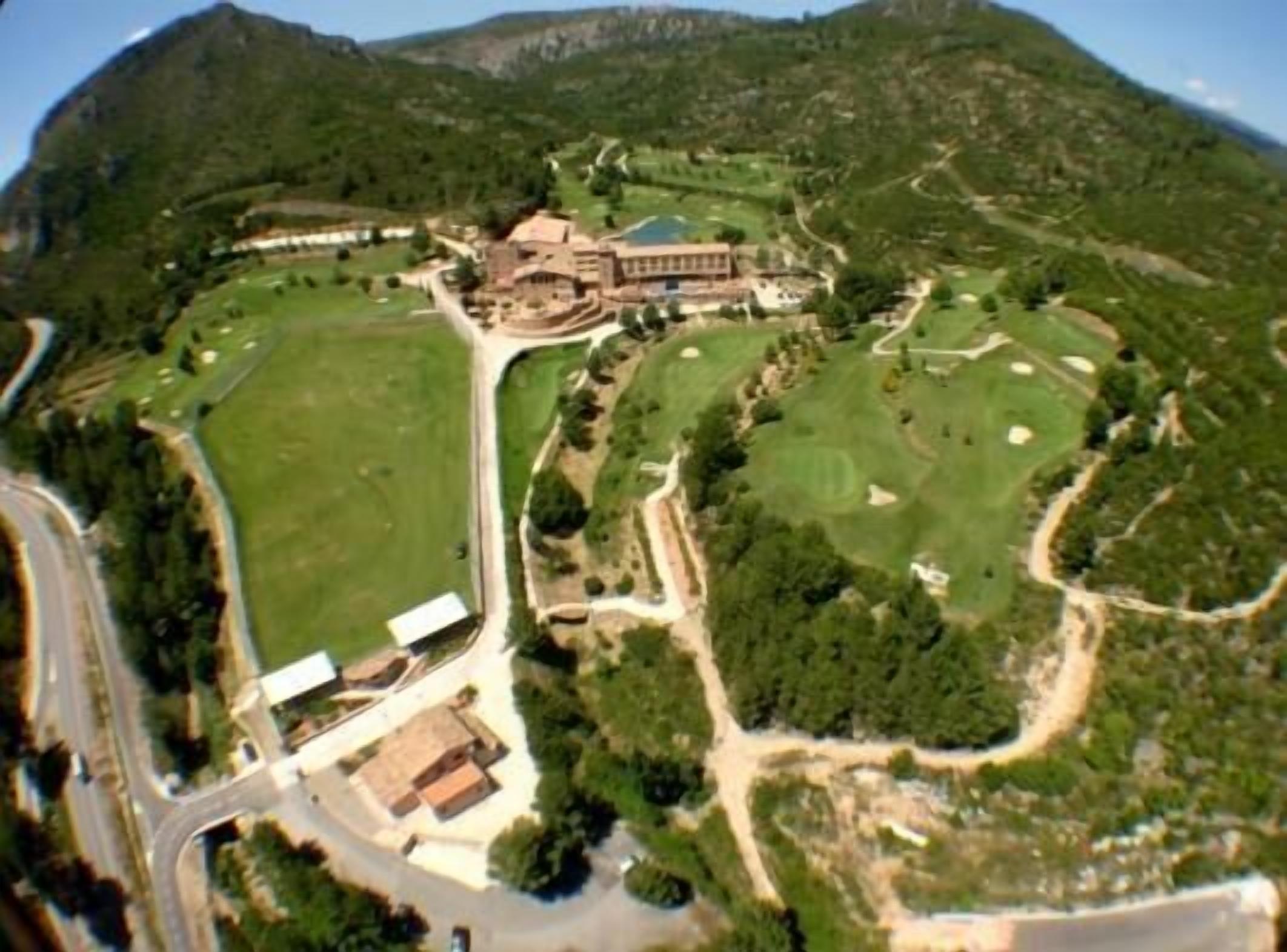 Un vaste domaine dont le bâtiment principal est entouré de grands espaces verts et d’un terrain de golf.