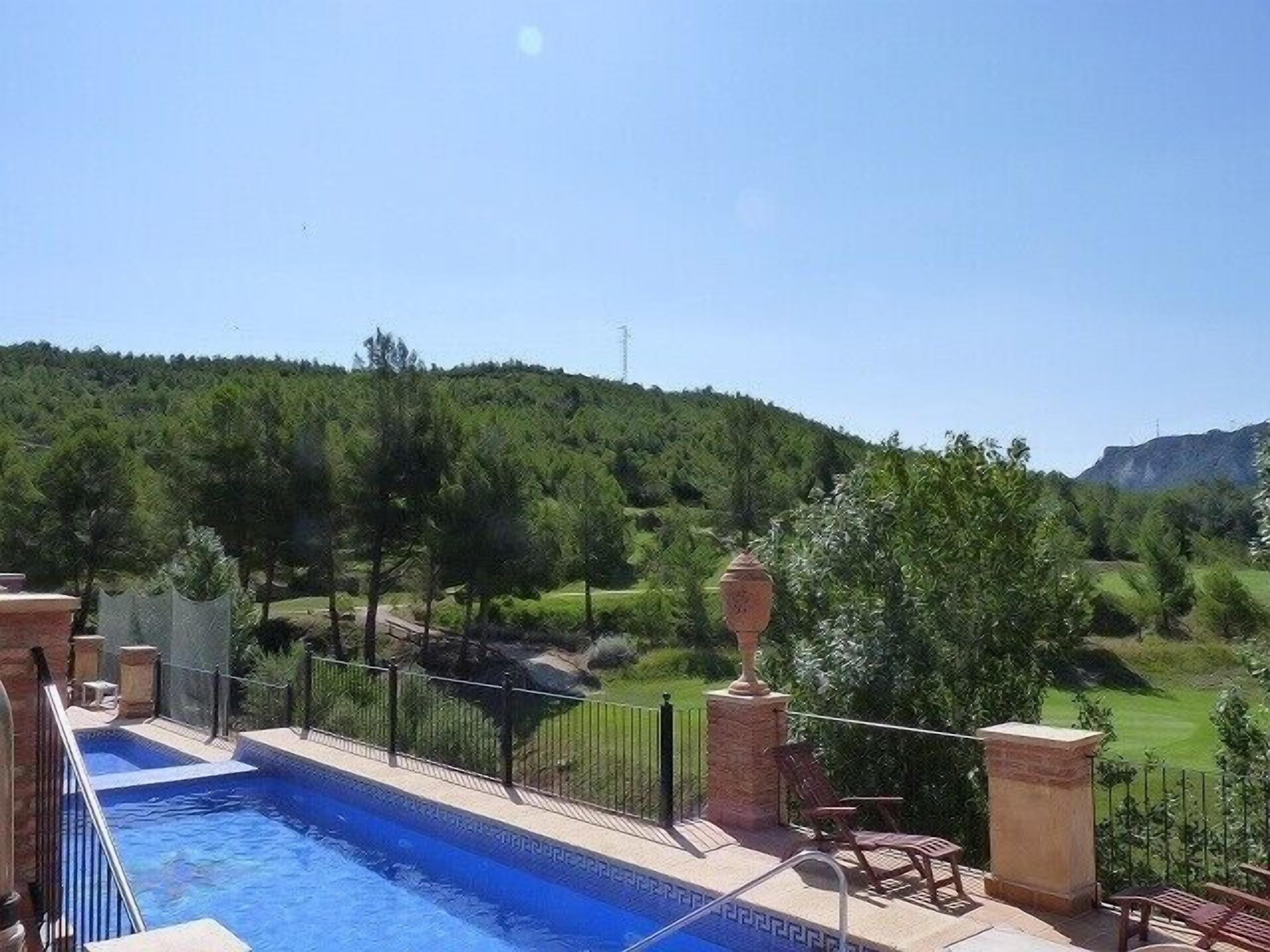 Una piscina con vistas a un paisaje verde y una montaña al fondo.