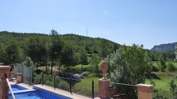 Una piscina con vistas a un paisaje verde y una montaña al fondo.