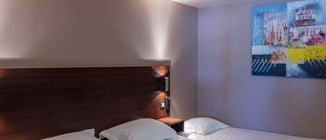 Une chambre d’hôtel avec un grand lit, une tête de lit en bois et une œuvre d’art fixée au mur représentant des paysages urbains.