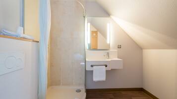 A modern bathroom with a shower, a sink, and a mirror.
