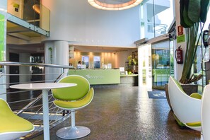 A reception area with a reception desk, green chairs, and a glass wall. - Riviera Beachotel - Recommended for Adults (Benidorm)