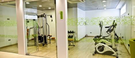 Un gimnasio con equipo de ejercicio, un espejo y un diseño de pared verde.