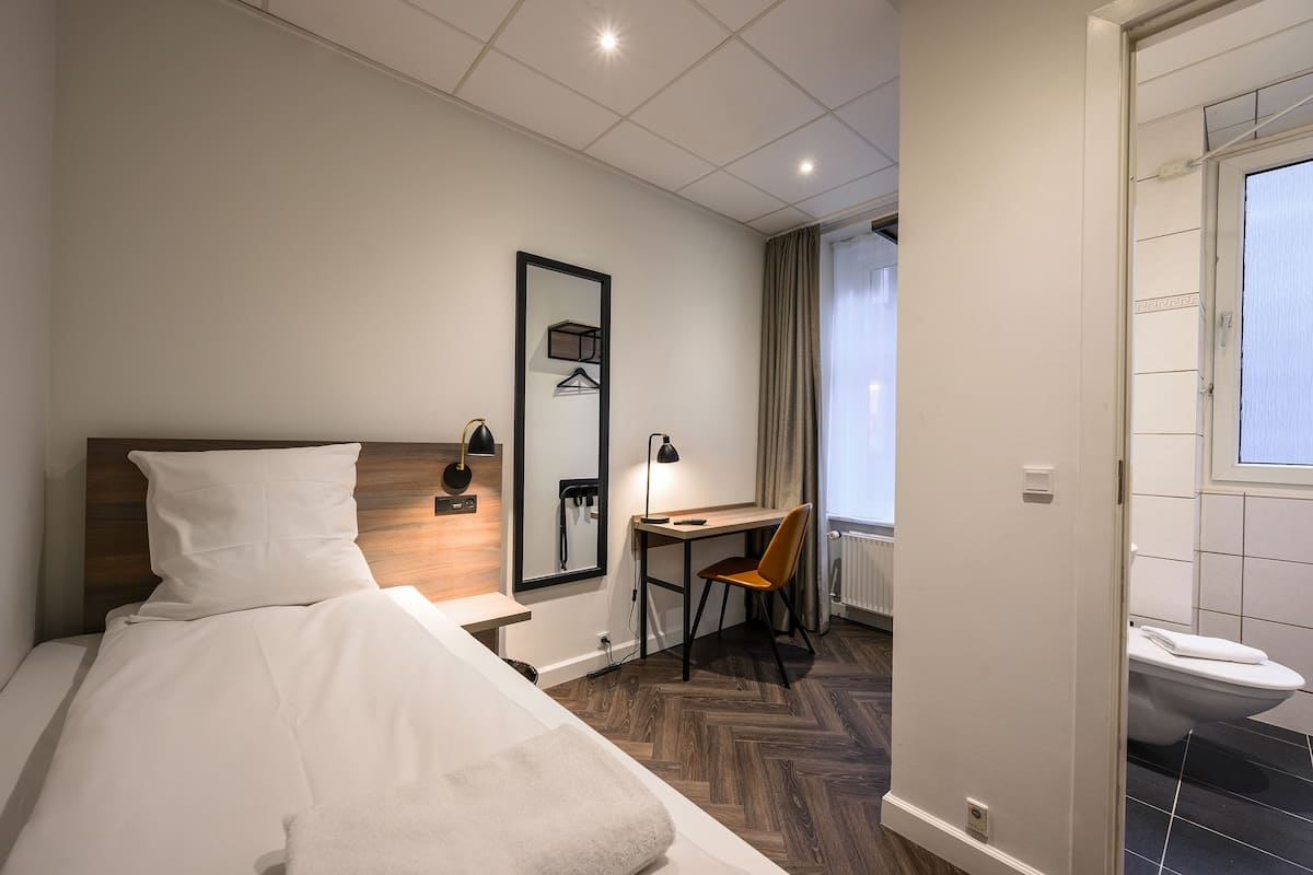 Une chambre d’hôtel équipée d’un lit, d’un bureau, d’une chaise, d’un miroir et offrant une vue sur l’extérieur.