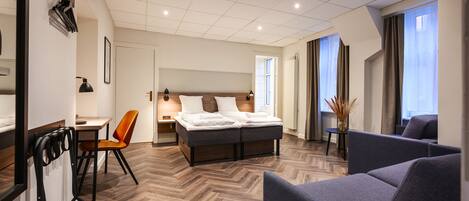 Une chambre d’hôtel moderne, dotée d’un grand lit, d’un bureau et d’un coin salon.