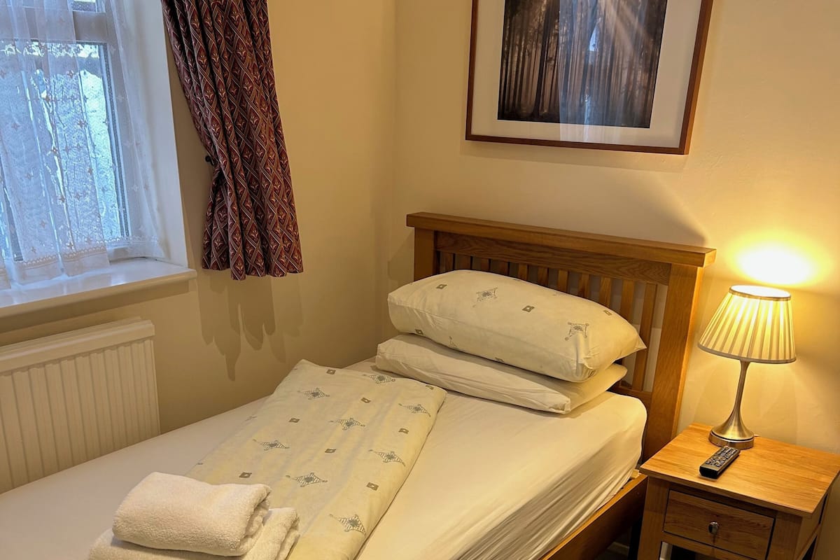 A neatly made bed with a wooden headboard, a bedside lamp, and a framed picture on the wall.