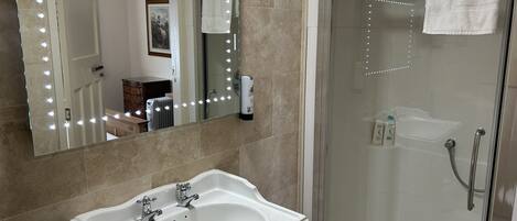 Un baño con lavabo, espejo y ducha.