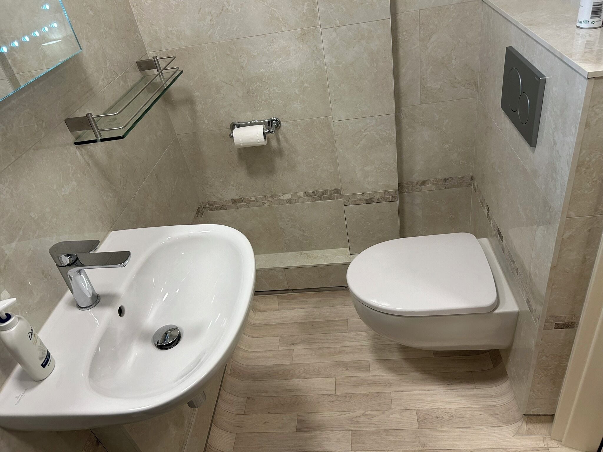 Ein Badezimmer mit einem weißen Waschbecken, einer Toilette und einem Glastischchen mit einem Handtuch.