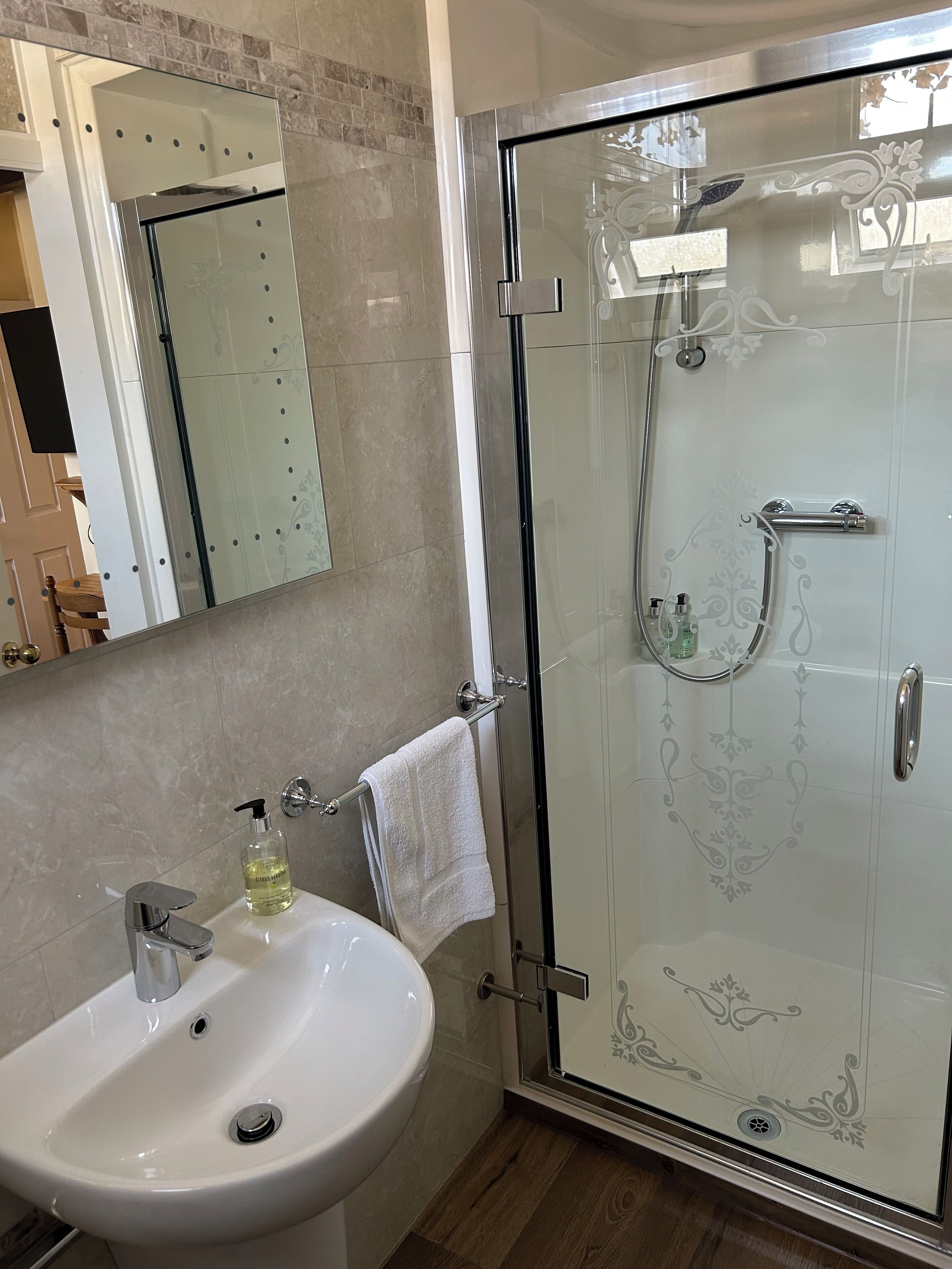 A modern bathroom with a glass-enclosed shower, a white sink, and a mirror.