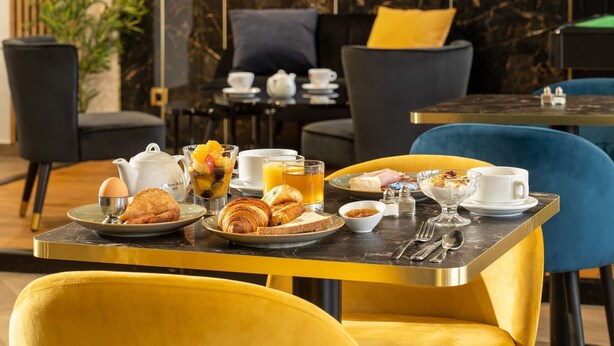Un desayuno con una mesa para dos, que incluye croissants, huevos y fruta.