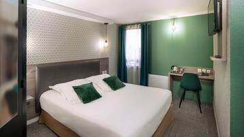 Ein Hotelzimmer mit Bett, Schreibtisch, Stuhl und Fernseher.