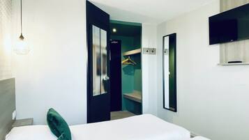 A hotel room with a large bed, a television mounted on the wall, and a door leading to a bathroom.