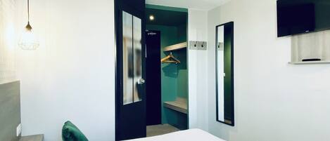 A hotel room with a large bed, a television mounted on the wall, and a door leading to a bathroom.