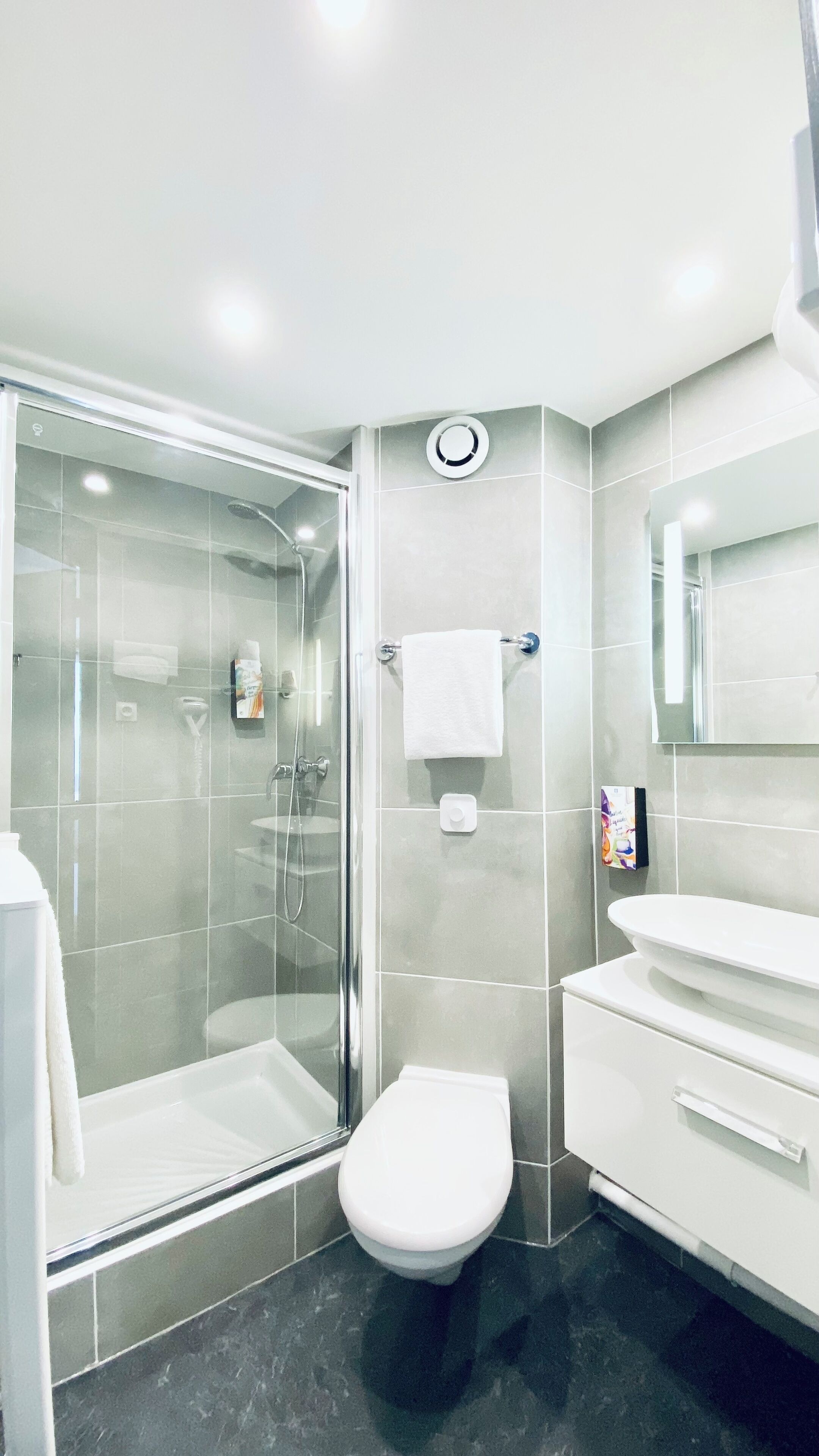 Une salle de bain moderne avec une douche à parois de verre, des toilettes blanches et un meuble-lavabo avec un miroir.