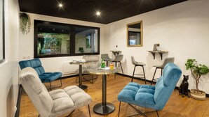Una habitación moderna con una mesa redonda, cuatro sillas, un sofá, un ventanal grande y una planta pequeña.