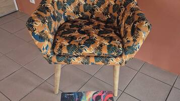 A chair with a floral pattern and a magazine titled "Superba" on a round table.