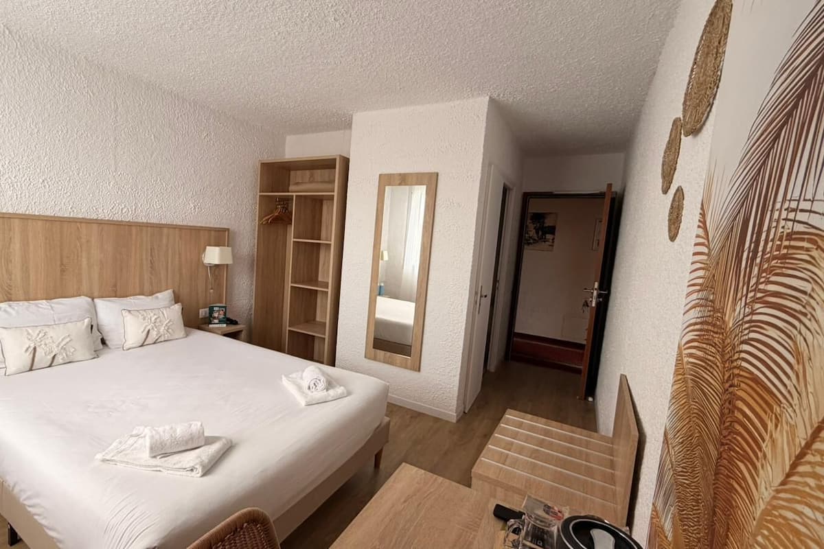 Quarto de hotel com uma cama grande, mesas de cabeceira, um guarda-roupa e um espelho.