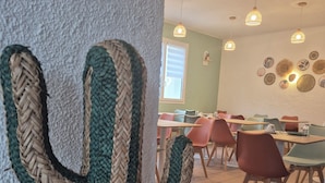 A dining area with a cactus decoration, tiled floor, and modern lighting fixtures.