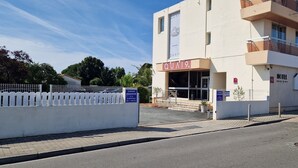 A hotel with a modern facade, a visible entrance, and a parking sign indicating reserved parking for hotel clients.