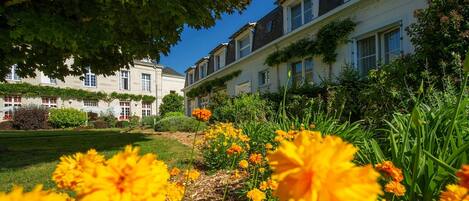 Een rij traditionele gebouwen in Europese stijl, met een verzorgde tuin op de voorgrond met gele bloemen.