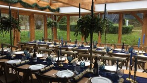 A large, open-air dining area with multiple tables set for a meal, featuring blue glassware and candles. - Bickleigh Castle Hotel (Tiverton)