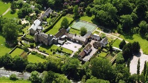 An aerial view of a historic estate with a tennis court, manicured gardens, and a river. - Bickleigh Castle Hotel (Tiverton)
