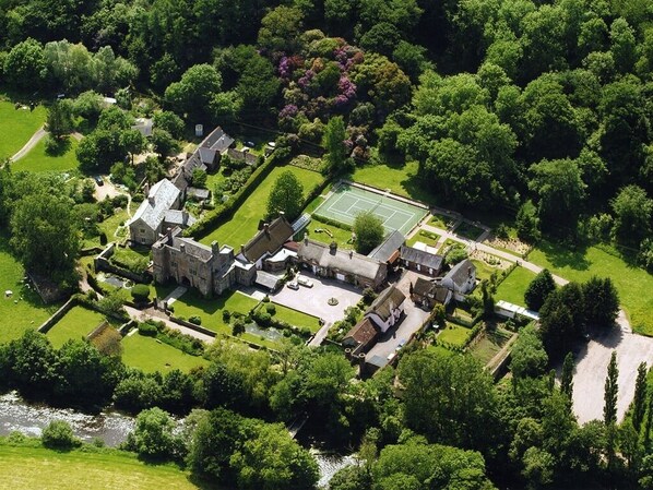 An aerial view of a historic estate with a tennis court, manicured gardens, and a river. - Bickleigh Castle Hotel (Tiverton)