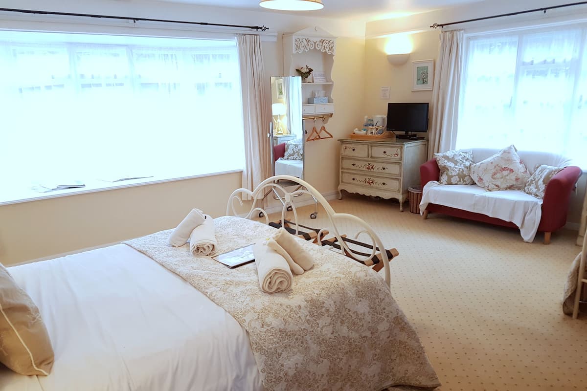 A hotel room with a bed, a sofa, a TV, and a dresser.