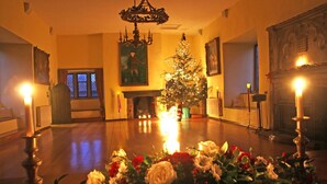 A warmly lit room with a Christmas tree, a fireplace, and a chandelier. - Bickleigh Castle Hotel (Tiverton)
