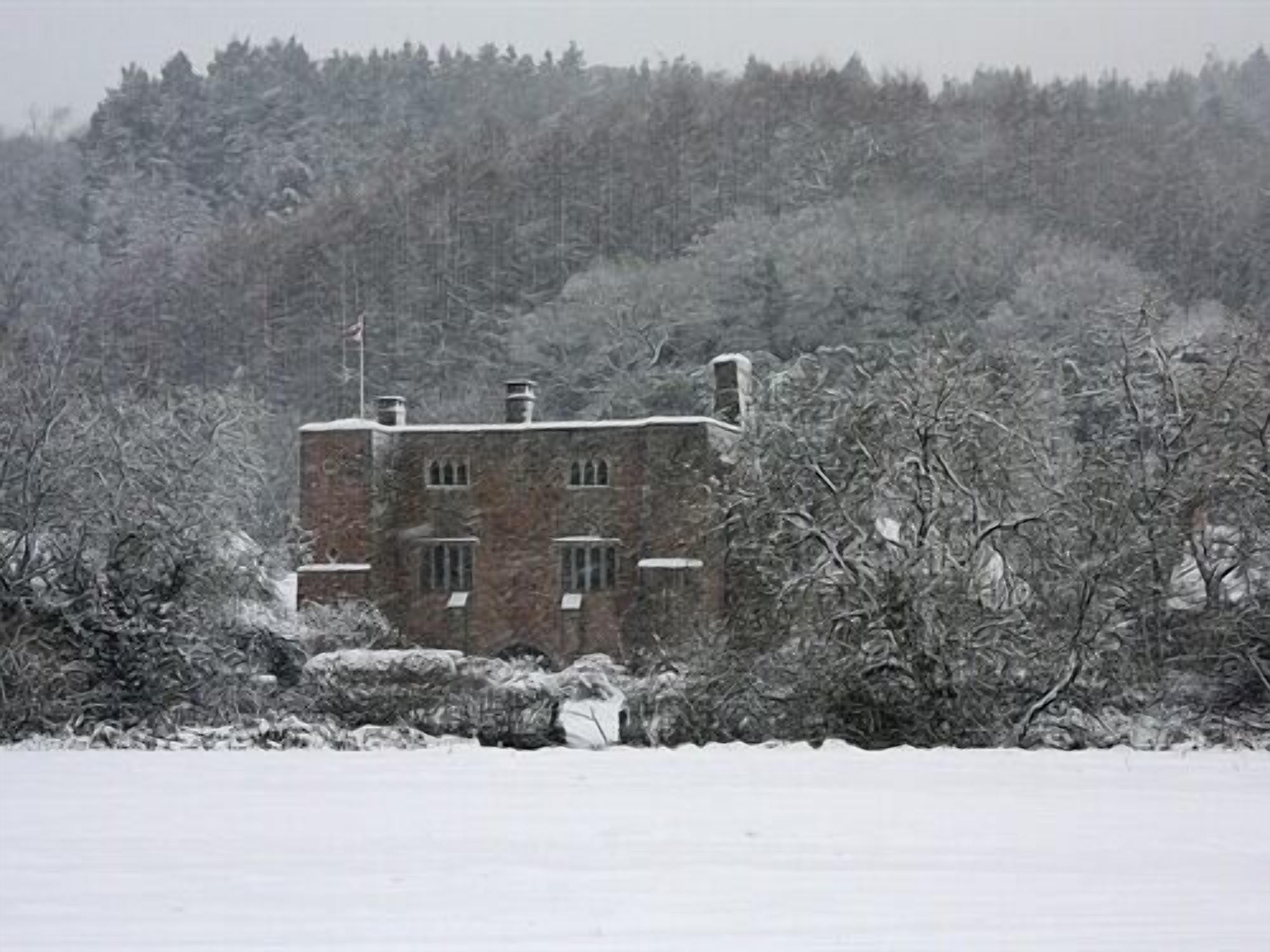 A stone building with multiple windows, surrounded by snow-covered trees and a snowy landscape.