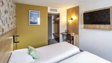 A hotel room with two beds, a wooden desk with a chair, a mounted TV, and a poster on the wall.