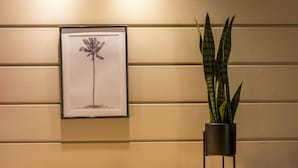 A framed artwork of a palm tree on a wall, a potted plant in a black pot, and a wooden table with a drain. - Ostal Pau Université - Sure Hotel Collection by Best Western (Pau)